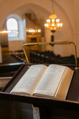 An open holy book rests at the front, gazing out over the church, where the chandelier glimmers above the nave
