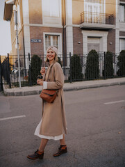 Beautiful young woman in coat walking around european city