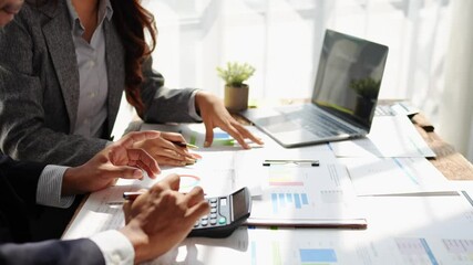 Young colleagues discuss business and analytical price charts using calculators and laptops to calculate financial, tax, accounting, statistics and analytical research ideas. - Powered by Adobe