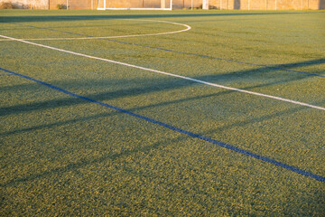 artificial turf sports field with white markings at sunset