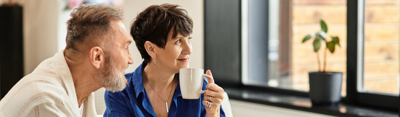 Middle aged couple enjoying a cozy moment at home with warm smiles and coffee in hand