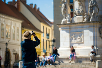 Man in the hat photographing in the street of the old town