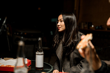 Girl enjoying pizza at a table with friends during a night out in a cozy setting