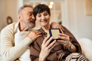 Joyful middle aged couple sharing a special moment at home with a heartfelt surprise