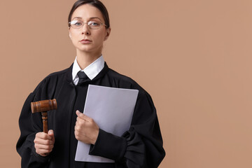 Judge with mallet and documents on light brown background, space for text