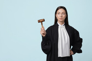 Judge with mallet on light blue background, space for text
