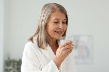 Smiling woman with glass of collagen water at home