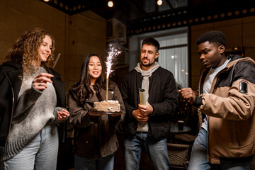 Friends celebrate a birthday indoors with cake and sparklers during a festive gathering