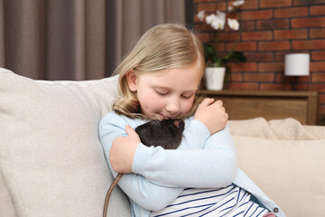 Obraz premium Little girl with cute black rat on sofa at home