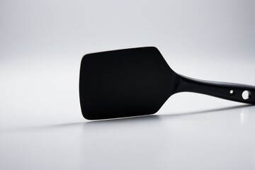 A black spatula sits on top of a white table, ready for use