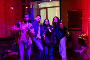 Group of friends celebrating at a vibrant evening gathering with drinks in hand