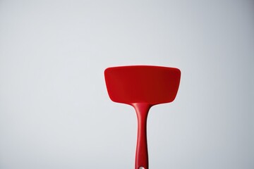 A bright red spatula sits on a kitchen counter, ready for use
