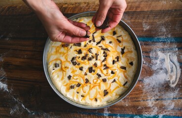 Young hands sprinkle chocolate over a prepped cake, embodying the essence of baking traditions and the joy of childhood memories in a rustic kitchen environment filled with flour