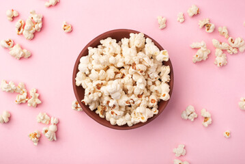 Tasty salty popcorn in a bowl on a pink background