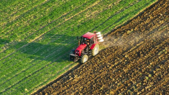 Tractor plowing a bright green field in the early morning sunshine above