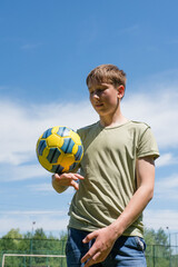 Naklejka premium Teenager skillfully juggling a soccer ball outdoors on a sunny day. A summer sports activity.