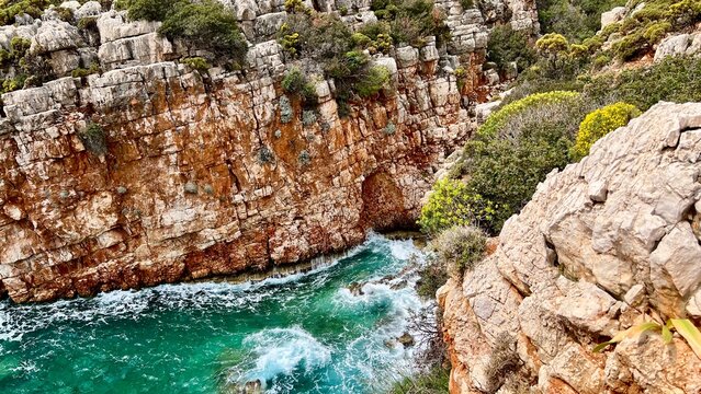 Horizontal photo of sea bay with bright blue water surrounded by rocky cliffs, Mediterranean Sea, Greece, Kastellorizo island, coastal landscape, travel destination, summer vacation, tourism. 