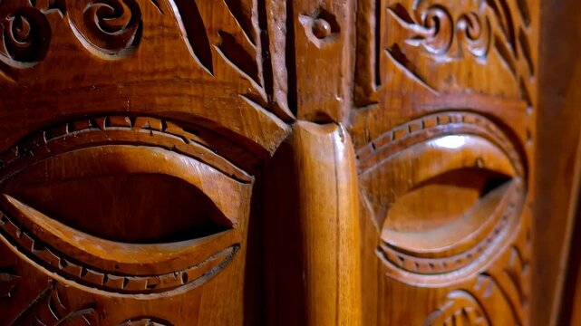 Detailed close-up of a traditional carved wooden face mask with intricate designs and a warm brown color, showcasing craftsmanship.