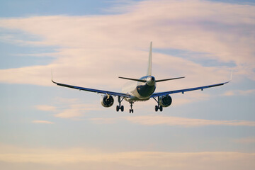 Rear view of a passenger airplane preparing to land at the airport at sunset.