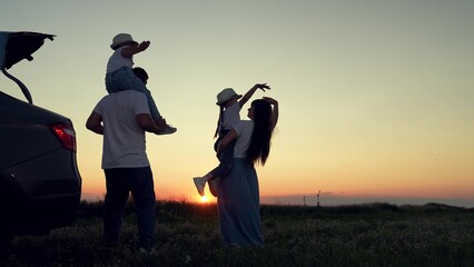 Dad with child, daughter on his shoulders, mom, children dance and admire beautiful sunset. Parents...