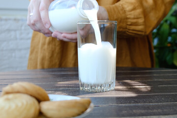 Woman drinking milk. Pouring milk into transparent glass