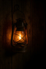 A warm, glowing vintage lantern casting light in a dimly lit wooden room, evoking a sense of nostalgia and rustic charm.
