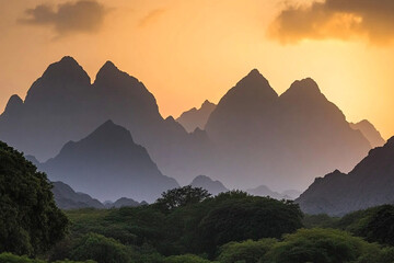 Silhouette of a stunning mountain range at sunset with dramatic peaks and lush greenery in the foreground