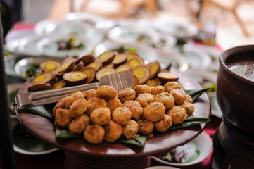 Perkedel, Indonesian fried delicacies, are displayed on a wooden platter. They consist of mashed...