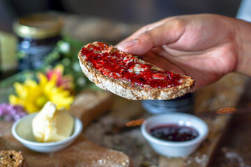 Close up of hand holding a slice of bread with Strawberry Jam
