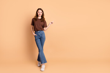 Young woman in casual clothing pointing and smiling against beige background, perfect for...