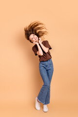 Cheerful woman posing stylishly in casual outfit on beige backdrop portraying charm and expressiveness