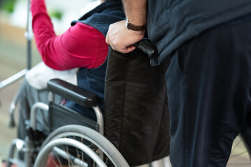 Wheelchair Assistance Close Up.Partial view of a person assisting someone in a wheelchair, showing hands and wheels.