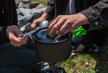 Young family camping on a hilltop with valley views. Pitching a tent, cooking outdoors, drinking...