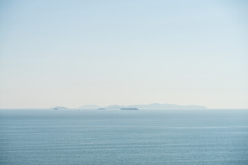 Foggy Light Blue Sea with Small Islands Near Horizon