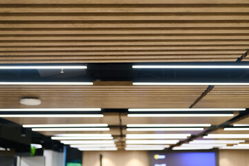 modern ceiling design featuring wooden panels and linear led lights in office interior