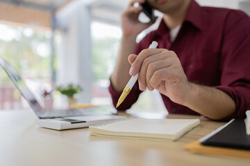A man is typing on a laptop at a desk with a calculator, a notebook, and a stack of books. Concept of productivity and focus, as the man is working on a task that requires concentration

