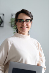 Confident young caucasian female wearing glasses with laptop in modern office setting