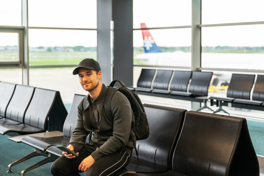 A passenger to Rome, waiting to board the plane.He uses his cell phone to pass the time.	
