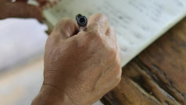 A hand writing on a notebook