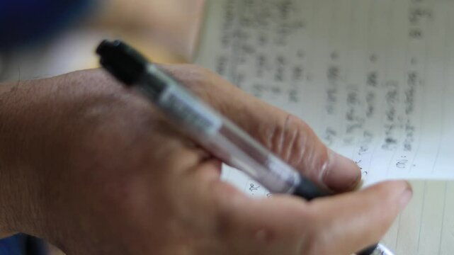 A hand writing on a notebook