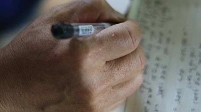 A hand writing on a notebook