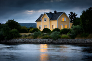 Obraz premium A charming yellow building sits peacefully by the river surrounded by trees.