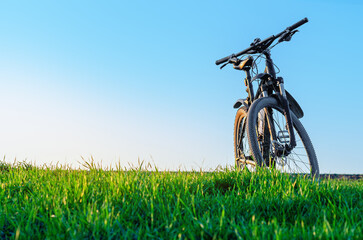 Sunlit bicycle on green field. Landscape with bicycle in spring. Outdoor recreation. Concept of...