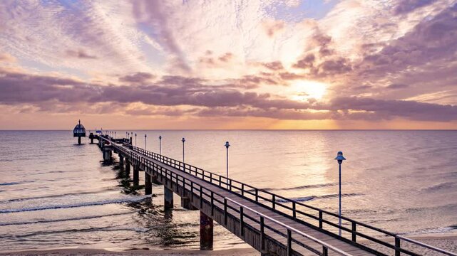 Zinnowitz, Usedom, Deutschland &ndash; Seebr&uuml;cke mit Tauchgondel im goldenen Morgenlicht des Fr&uuml;hlings. Timelapse Sonnenaufgang &uuml;ber der Ostsee, ruhige See, goldener Sand und erwachende Natur.	