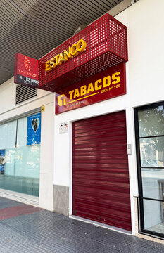 Malaga, Spain - May 18, 2025: Estanco tobacco shop with red signage and closed shutters, located on a street, showcasing urban architecture and commercial activity in a vibrant city environment