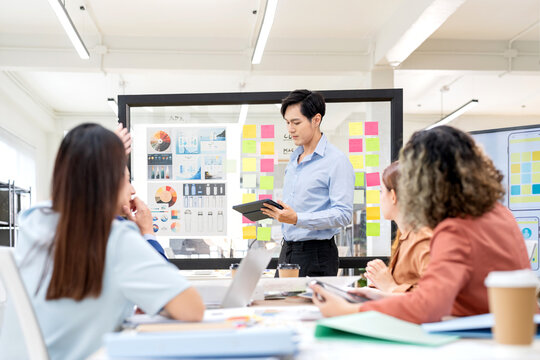 In a modern office, a diverse team of financial tech startup professionals gathers for a business strategy meeting, actively brainstorming innovative solutions, analyzing data, and discussing growth o