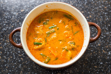 Massaman curry in a clay bowl with handles. Hot spicy Thai dish, top view