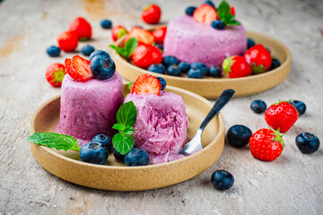 Frozen dessert- homemade blueberry strawberry frozen yogurt as shaved freezie with ice cream offered as close-up on a design plate