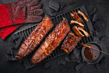 Barbecue spare ribs St Louis cut with hot honey chili marinade and barbecu dip sauce served as top view on a rustic grillage