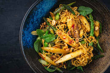 Stir fried Asian styly noodles with chicken filet and green and white asparagus and cashew nuts